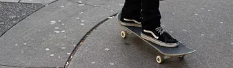 Young man riding his skateboard on gum stained concrete roadway