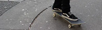 Young man riding his skateboard on gum stained concrete roadway